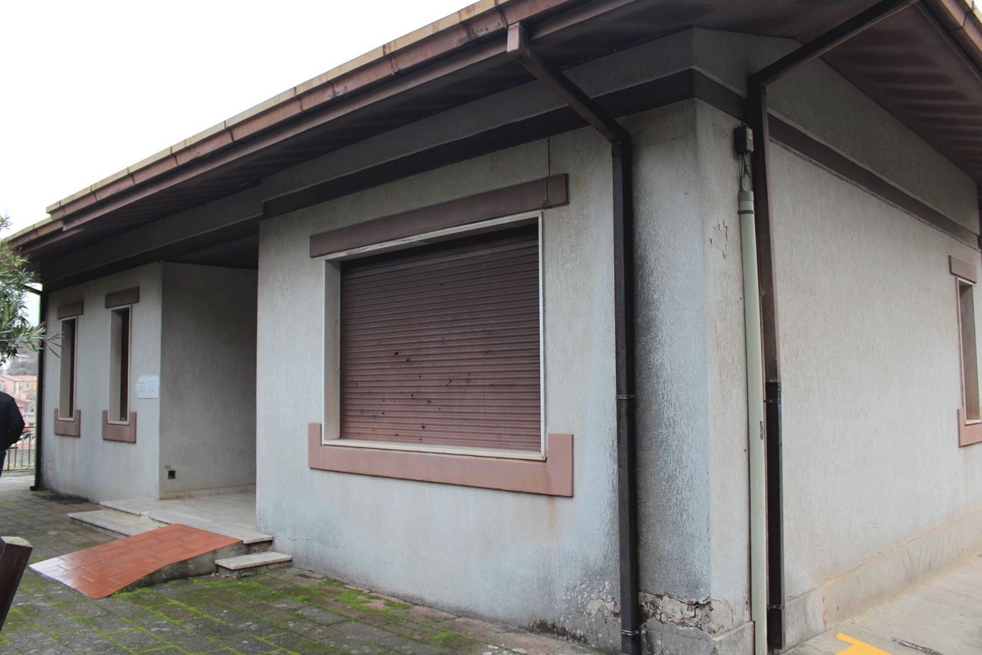 Ingresso principale dell'edificio ASL di Santu Lussurgiu con rampa per disabili e persiana chiusa.