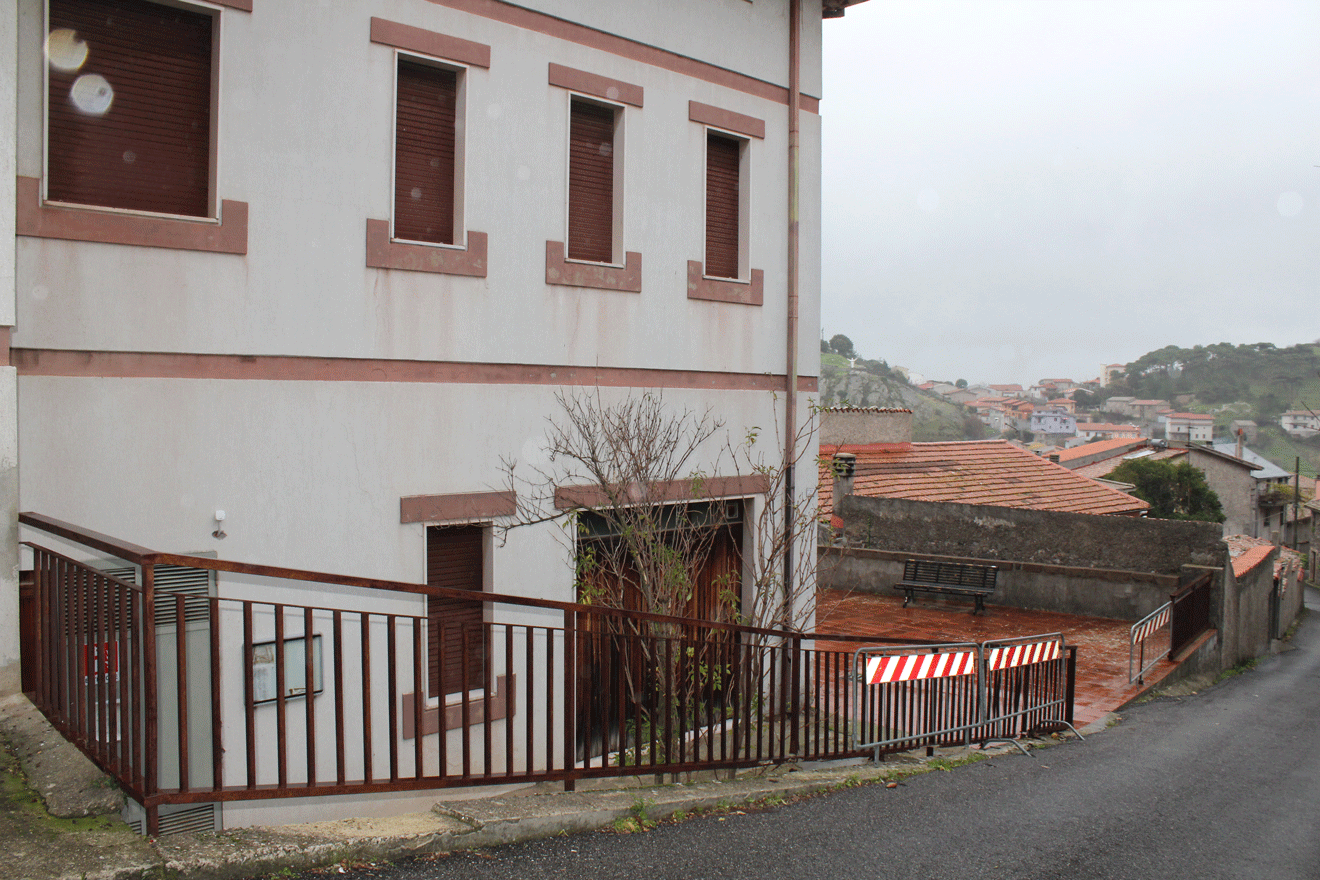 Vista dell'edificio ASL su più livelli con recinzione metallica e panorama di Santu Lussurgiu.