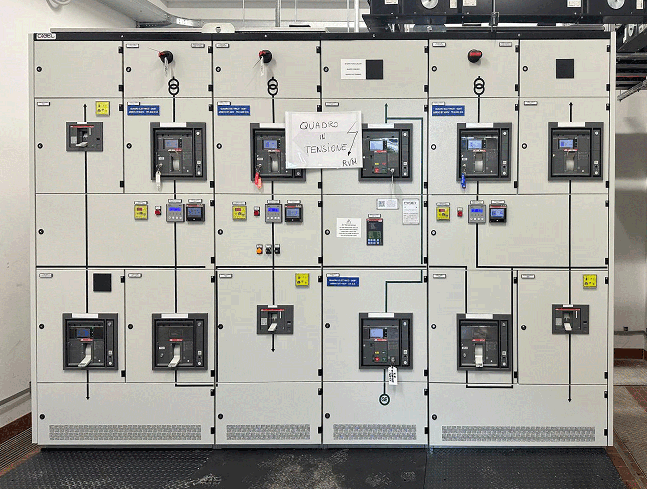 Ampio quadro elettrico generale di bassa tensione con display digitali e cartello "Quadro in tensione".