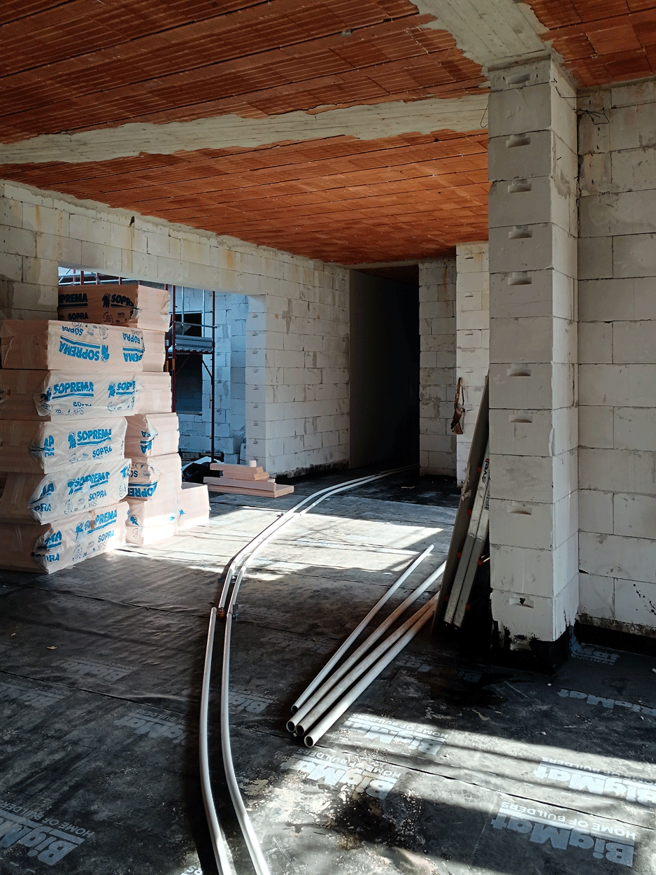 Posa delle tubazioni per impianti a pavimento e materiali isolanti nel cantiere dell'asilo.