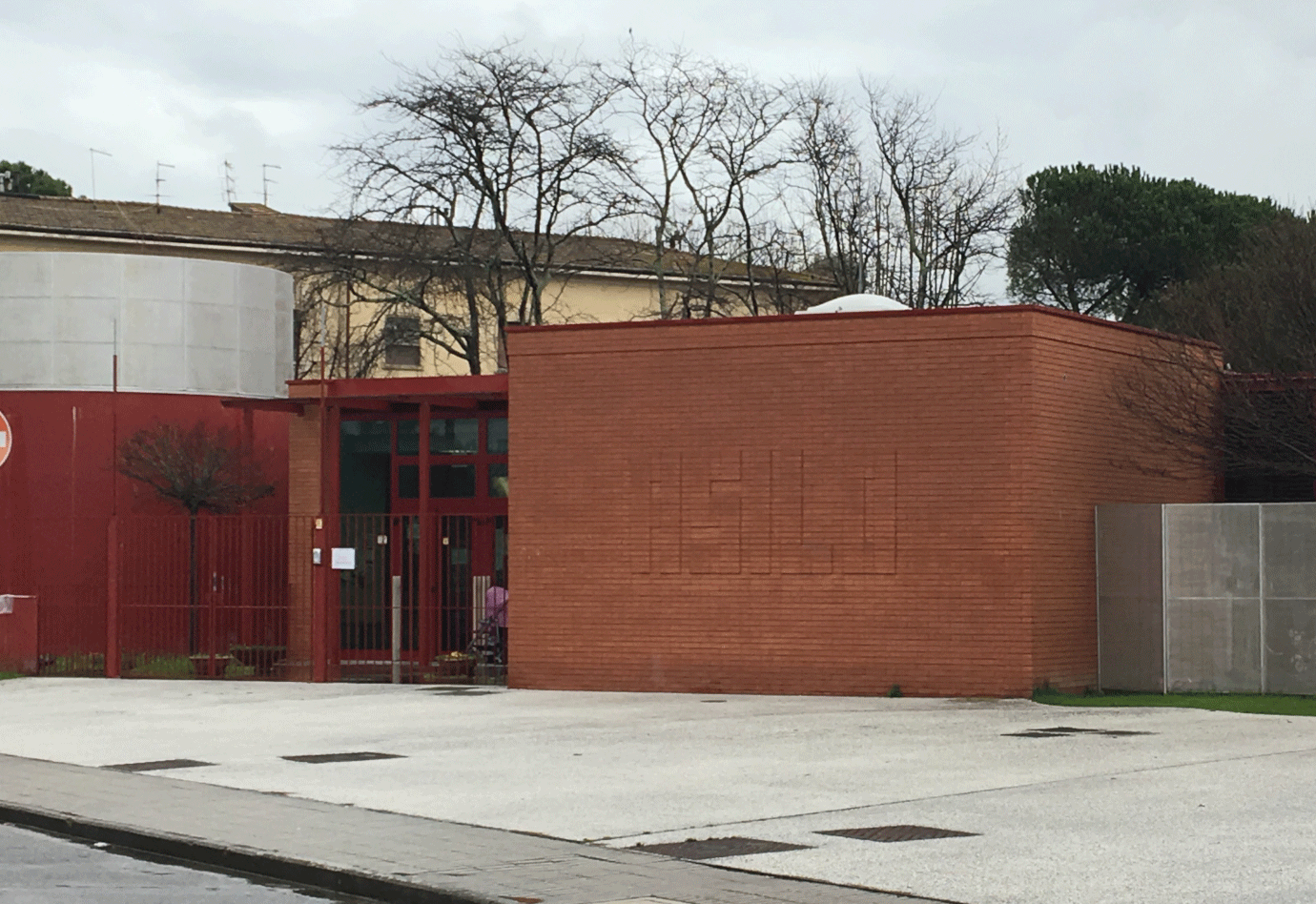 Ingresso principale di un asilo nido con scritta sulla parete in mattoni.