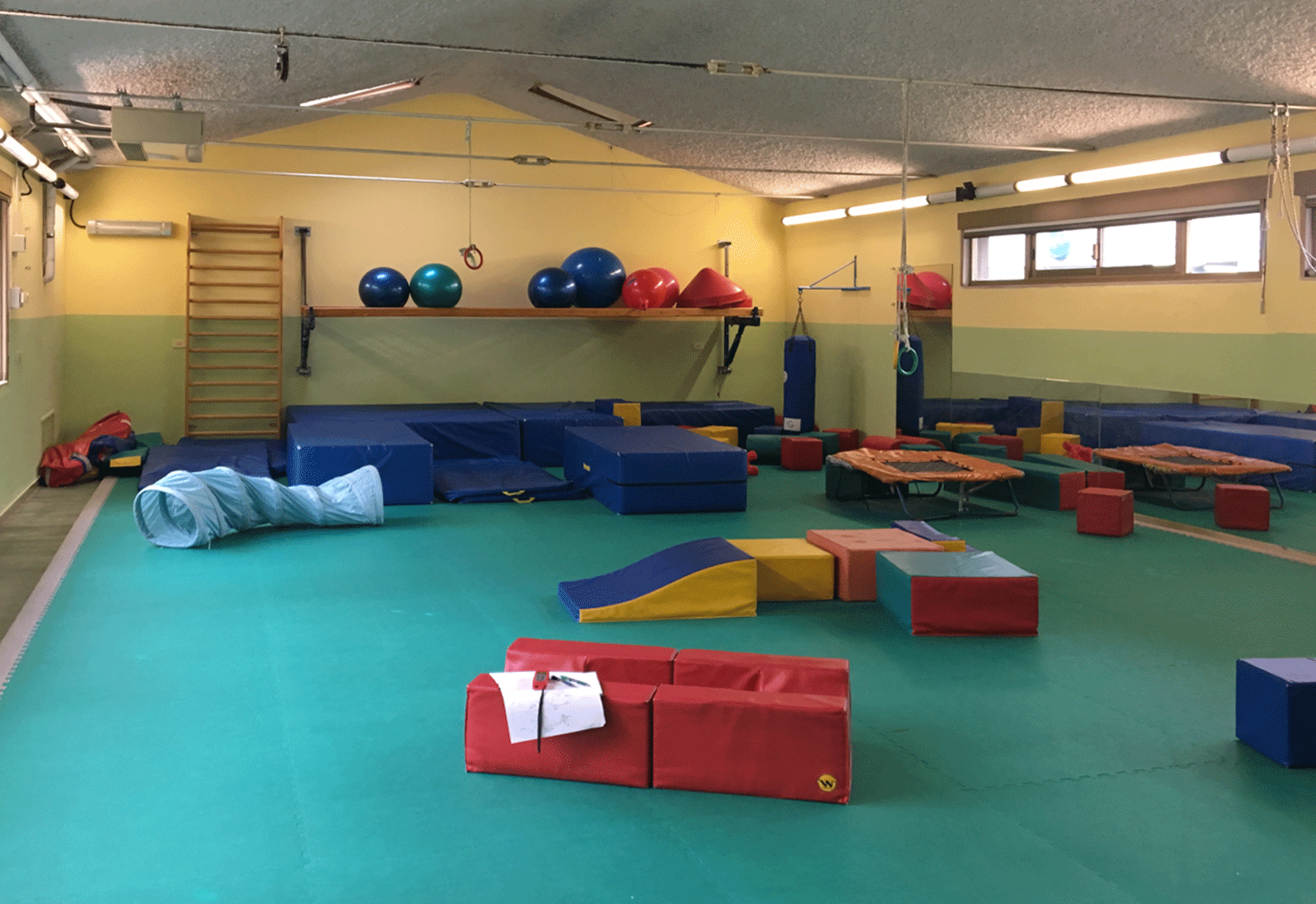 Palestra per psicomotricità con tappeti e grandi palloni colorati.