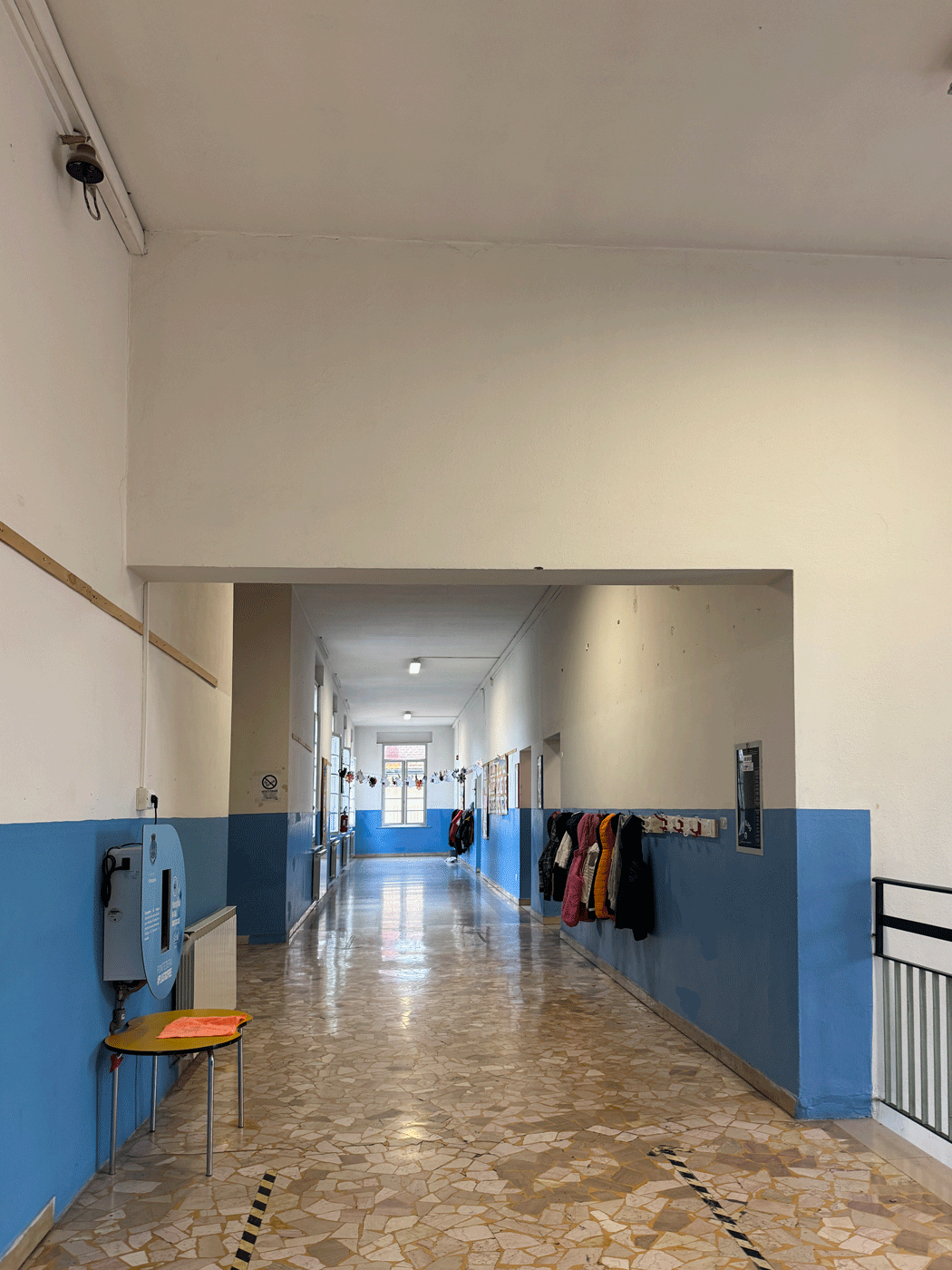 Lungo corridoio scolastico con pareti bicolori e pavimentazione in graniglia.