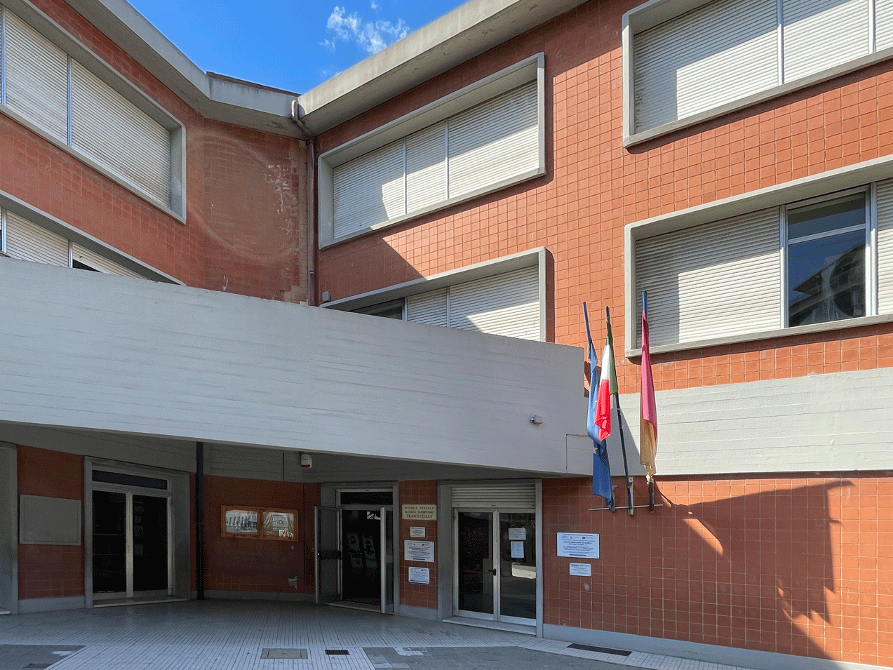 Ingresso moderno di una scuola con rivestimento in piastrelle rosse.