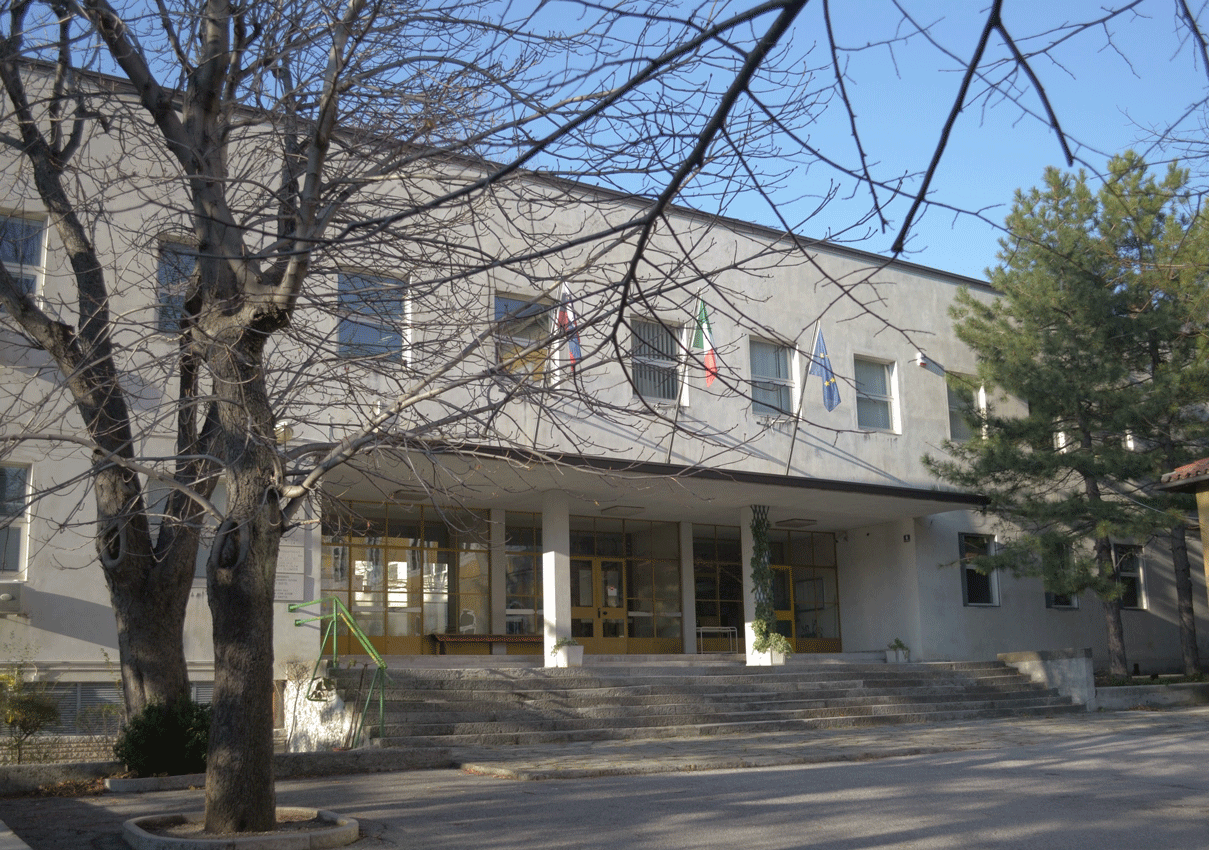 Ingresso principale del Liceo Slomsek con scalinata esterna, ampie vetrate e bandiere istituzionali.