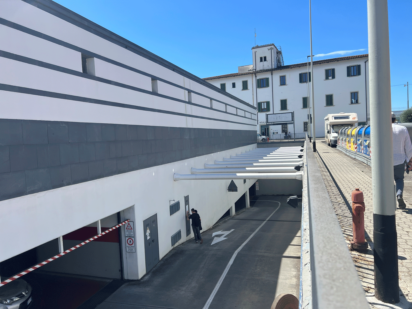 Rampa di accesso al parcheggio interrato Esselunga con vista sui sistemi di ventilazione e illuminazione esterna.