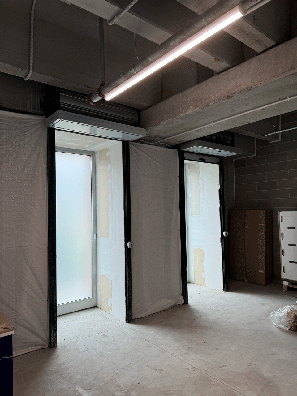 Fase di cantiere nel seminterrato del centro medico Varese con porte e tubazioni a soffitto.