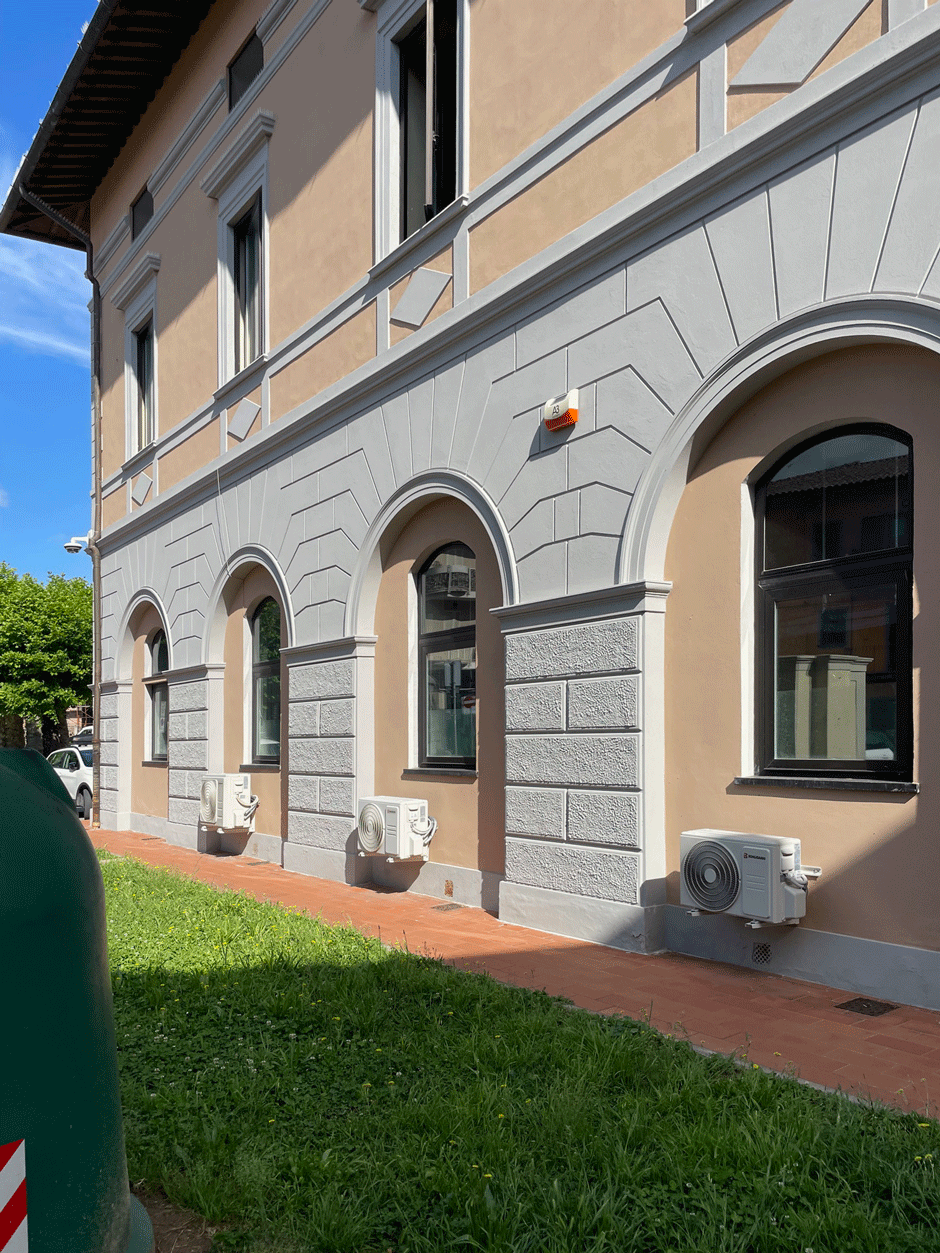 Particolare degli archi a piano terra e unità esterne di climatizzazione lungo il perimetro dell'ufficio.