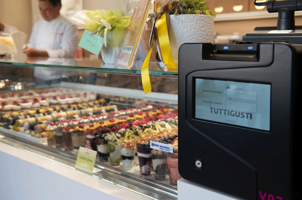 Dettaglio punto cassa e bancone refrigerato con illuminazione dedicata per gelateria.