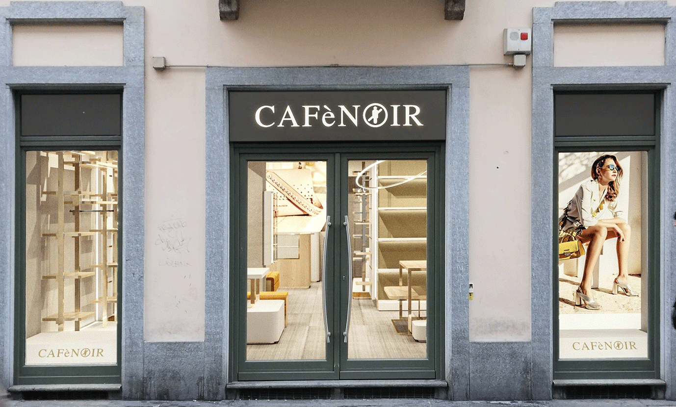 Facciata esterna di un punto vendita CafèNoir con vetrine espositive e insegna luminosa.