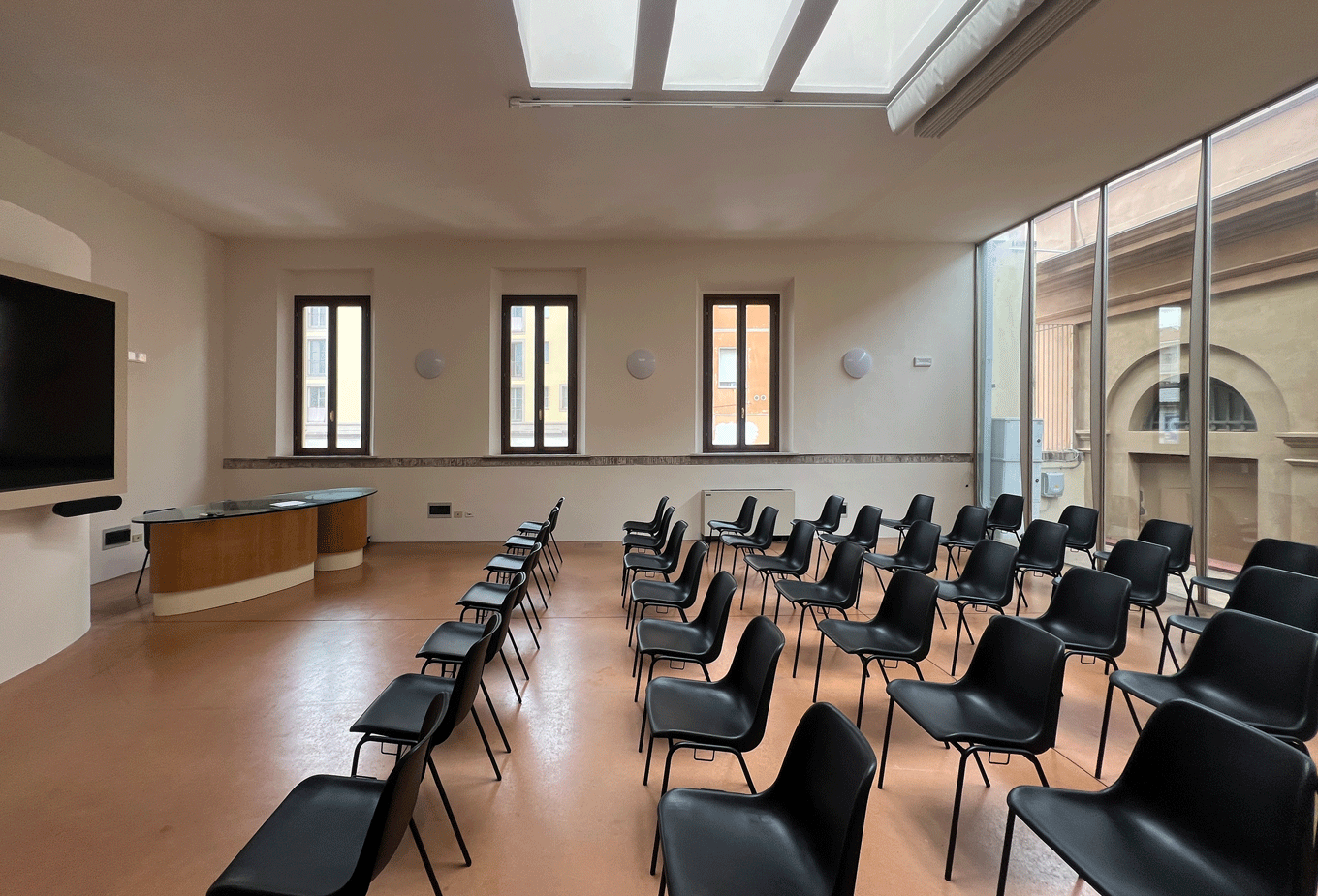 Sala conferenze interna della Stazione Leopolda con sedute nere e impianti audio EVAC integrati.