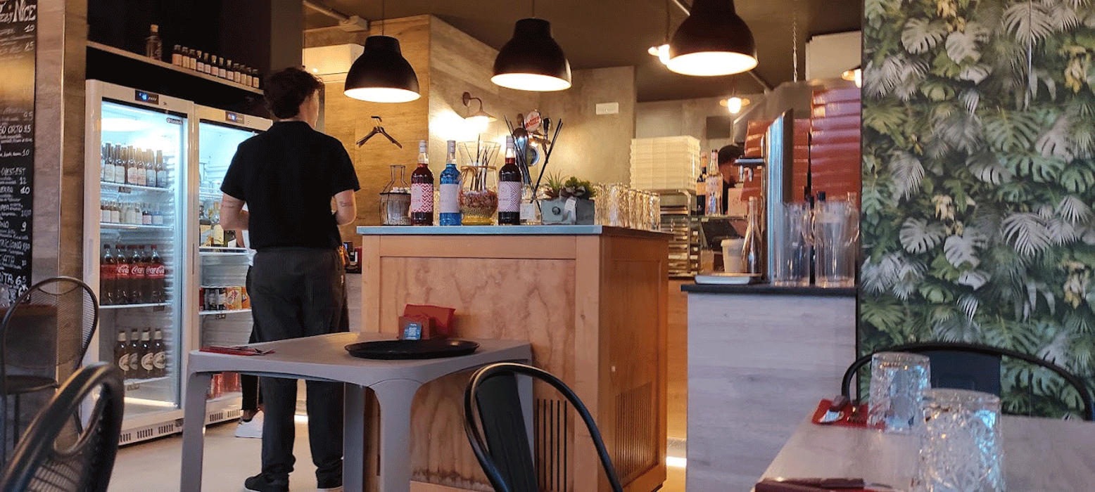Interno sala Pizzeria Nice con frigo bevande e tavoli pronti per il servizio.