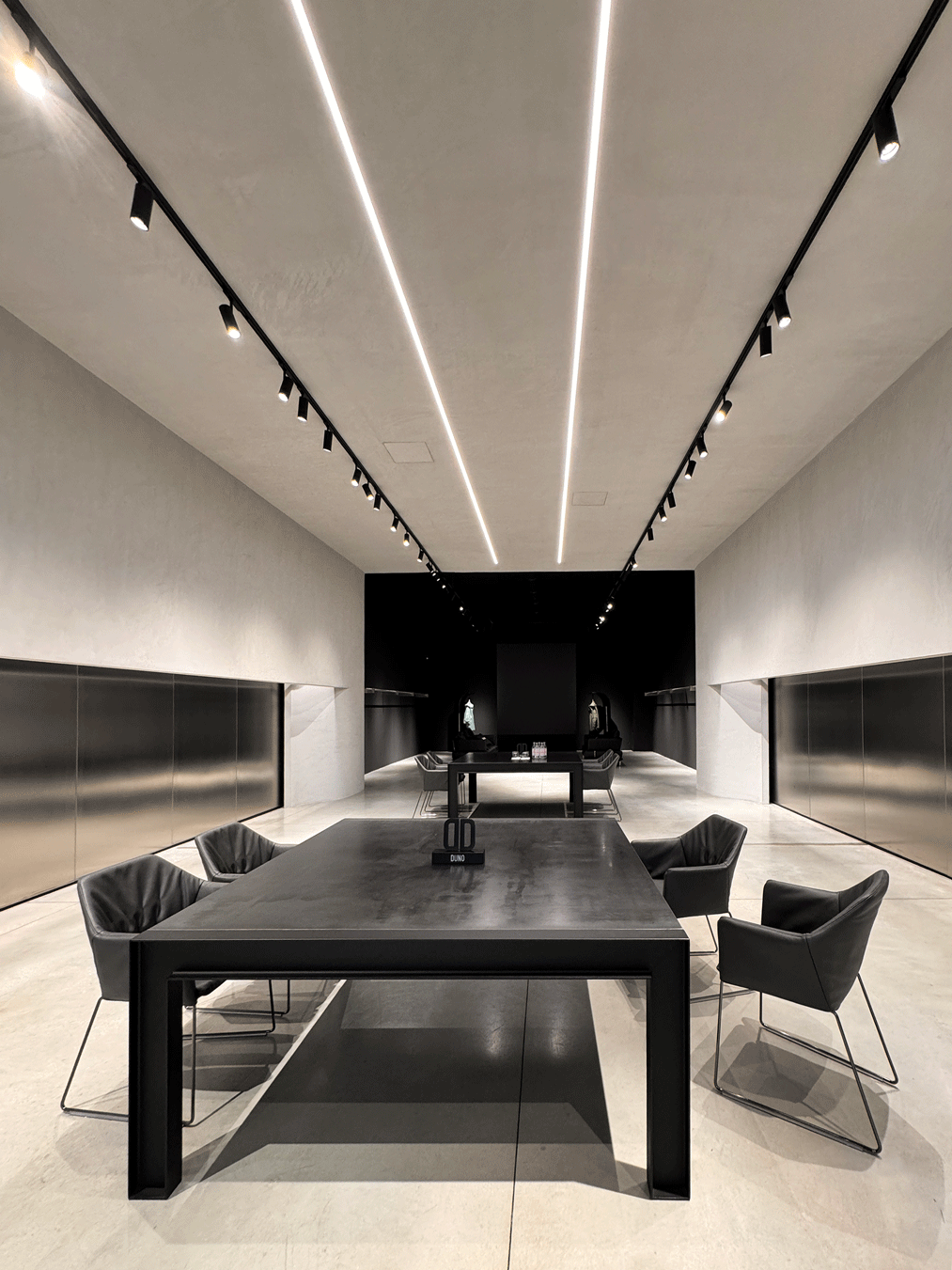 Spazio espositivo DUNO con tavoli, sedute e sistemi di illuminazione a binario e LED.