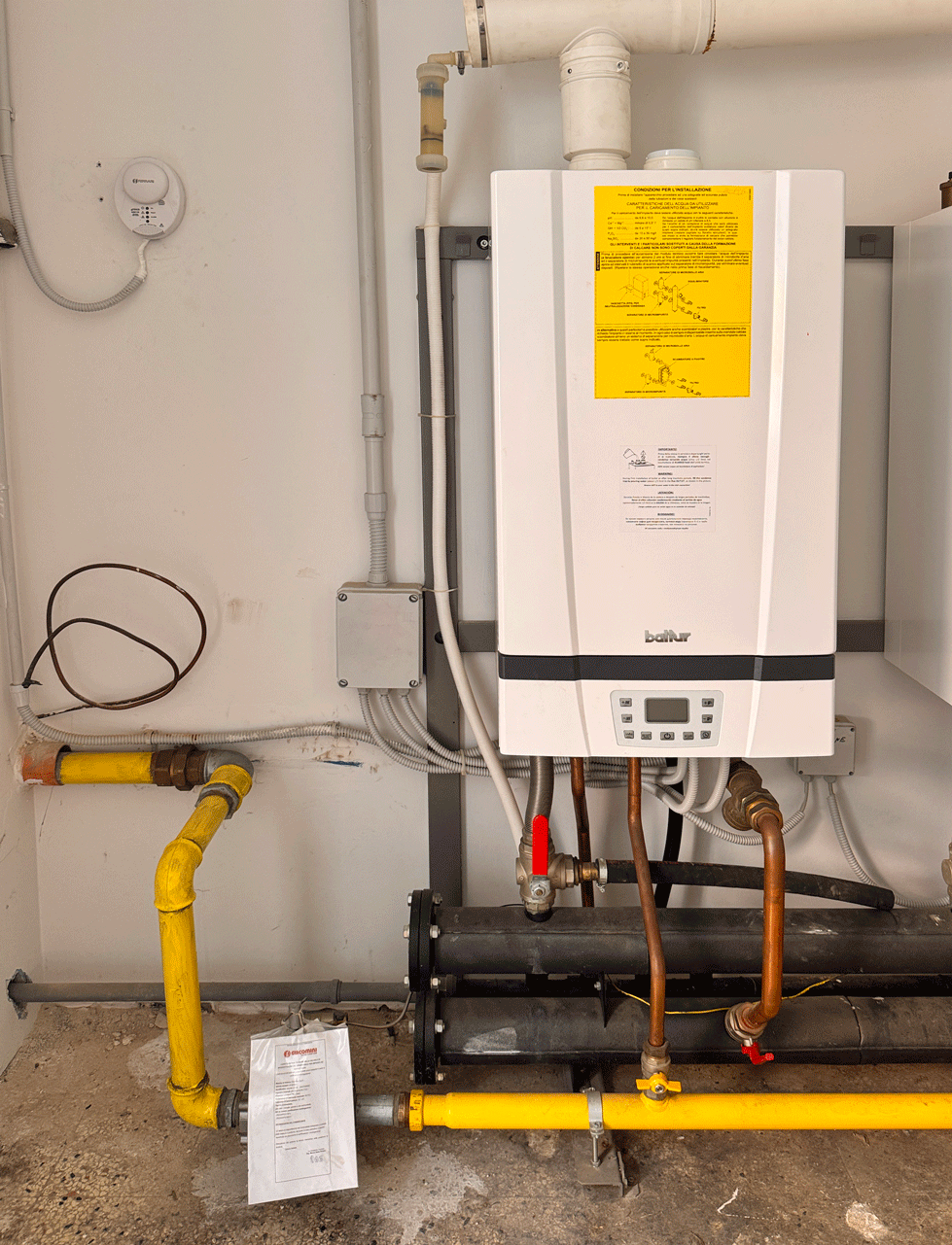 Generatore termico a gas con tubazioni nella centrale della scuola elementare di Chianni.