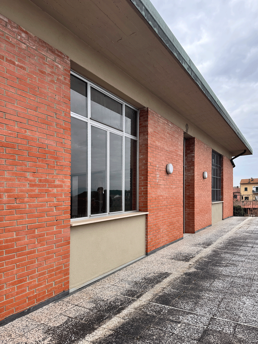 Terrazza esterna della Scuola primaria Carducci con facciata in laterizio e ampie finestre.