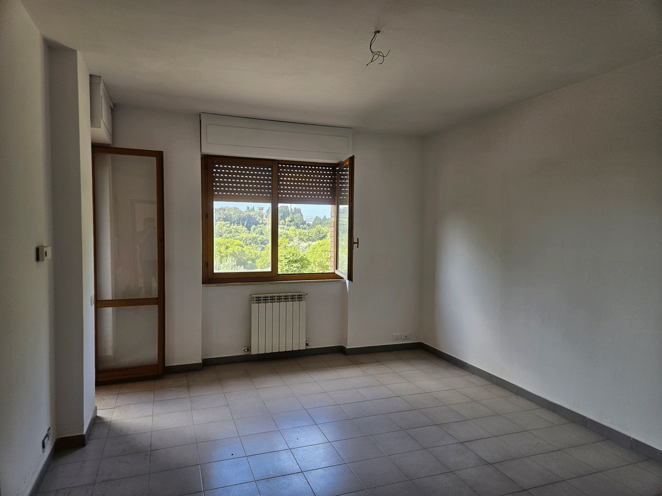 Ambiente interno di un appartamento Siena Casa con finestra e radiatore.