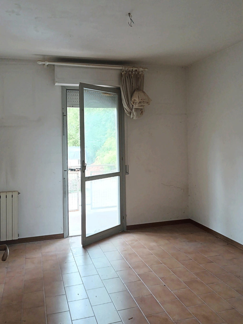 Ambiente interno di un appartamento Siena Casa con portafinestra e radiatore.